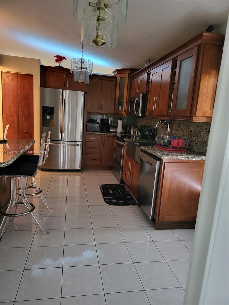 6771 Northwest 199th Terrace Hialeah, FL 33015 - Photo 38 of 42 a kitchen with granite countertop a refrigerator and a stove top oven