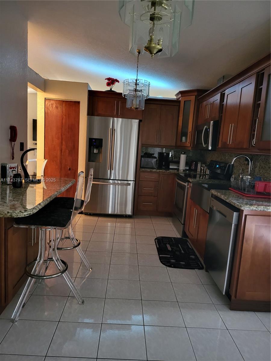 6771 Northwest 199th Terrace Hialeah, FL 33015 - Photo 42 of 42 a kitchen with granite countertop a refrigerator and a stove top oven