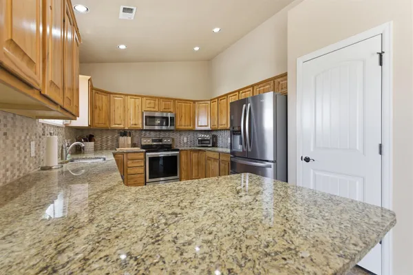 a kitchen with stainless steel appliances granite countertop a refrigerator sink and stove