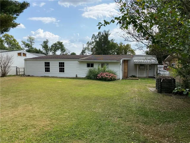 a front view of house with yard and trees in the background