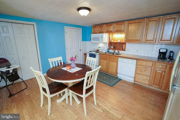 a kitchen with stainless steel appliances kitchen island granite countertop wooden floors and white cabinets