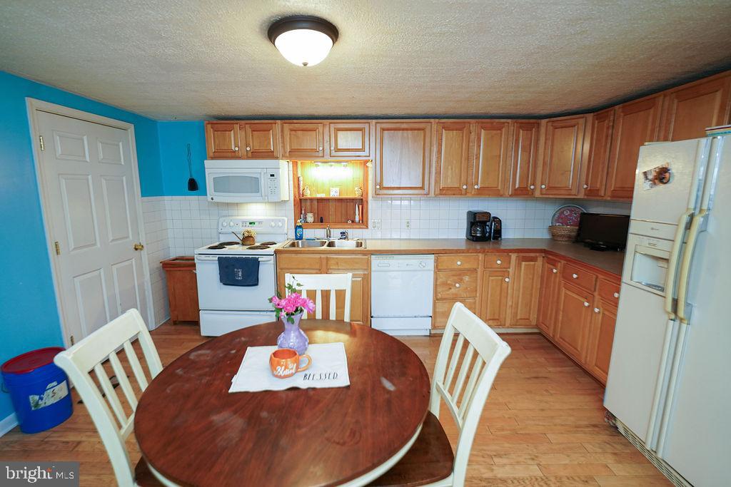 212 Main Street Preston, MD 21655 - Photo 9 of 40 a kitchen with stainless steel appliances granite countertop a sink dishwasher a refrigerator a stove top oven a dining table and chairs with wooden floor