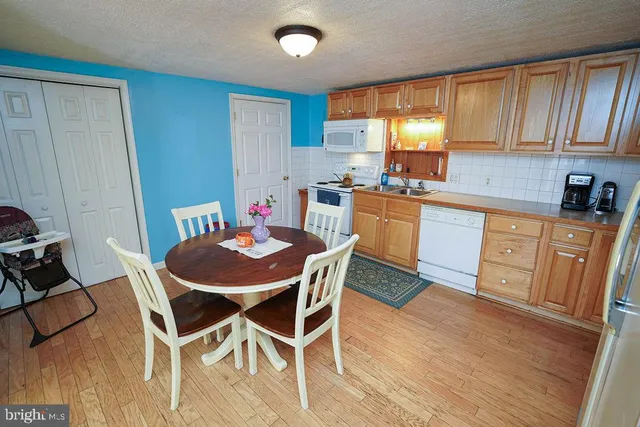 a kitchen with stainless steel appliances kitchen island granite countertop wooden floors and white cabinets