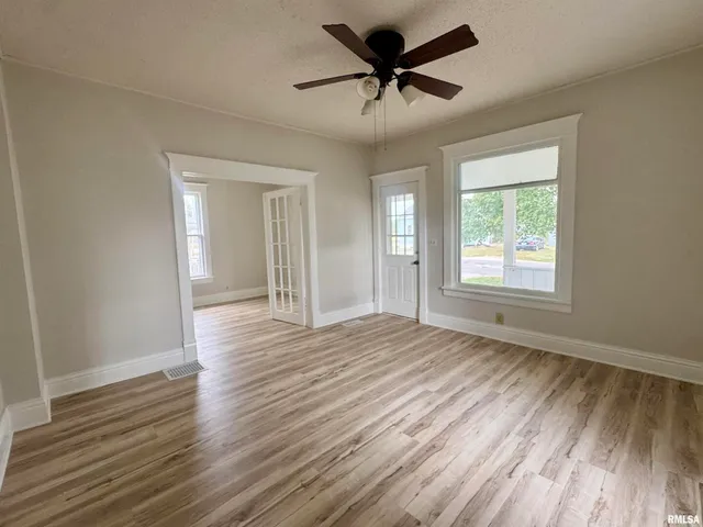 a view of empty room with wooden floor and fan