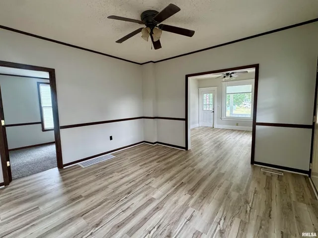 a view of a room with wooden floor and a ceiling fan