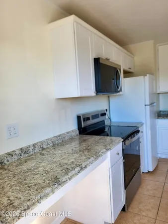 a view of an empty room with window and chandelier fan