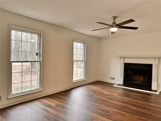 an empty room with wooden floor fireplace and windows