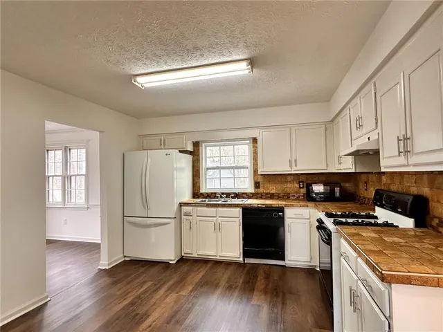 a kitchen with granite countertop a refrigerator stove top oven and sink