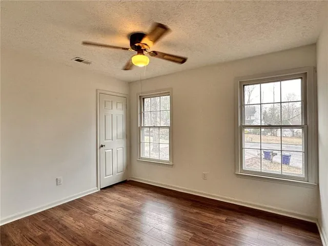 a view of an empty room with wooden floor and window