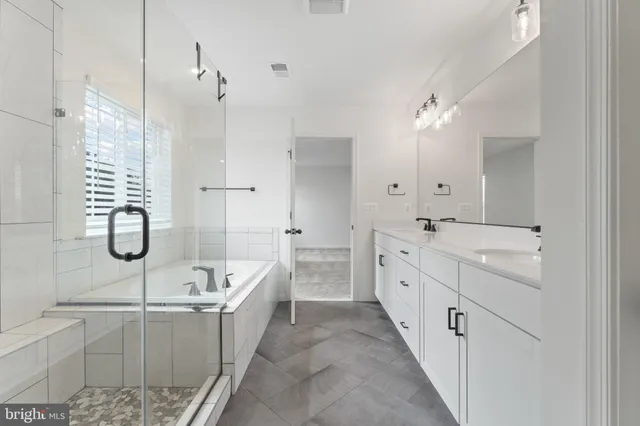 a spacious bathroom with a double vanity sink a mirror and a bathtub