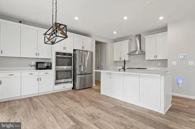a kitchen with white cabinets stainless steel appliances and wooden floor