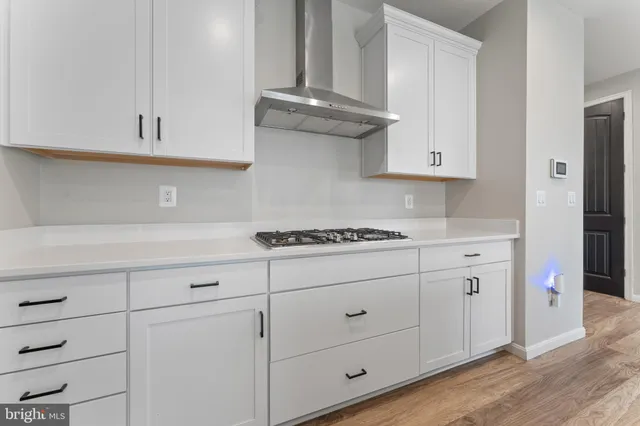 a kitchen with white cabinets and a stove with wooden floor
