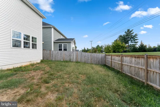 a view of a backyard with wooden fence and large trees