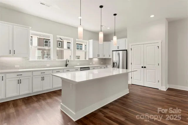 a large kitchen with granite countertop a sink a counter space appliances and cabinets