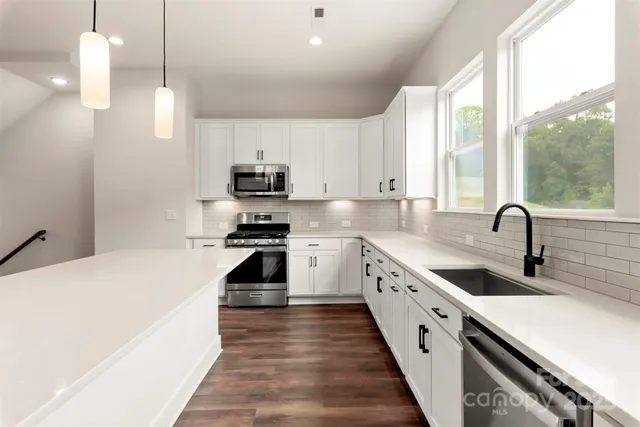 a large kitchen with stainless steel appliances granite countertop a sink a stove and a refrigerator