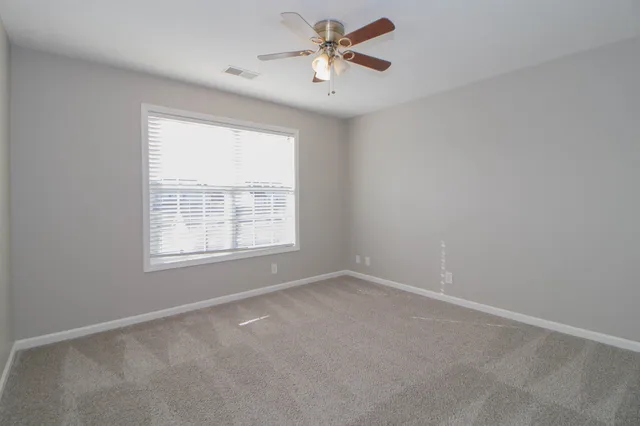 an empty room with a window and a fan