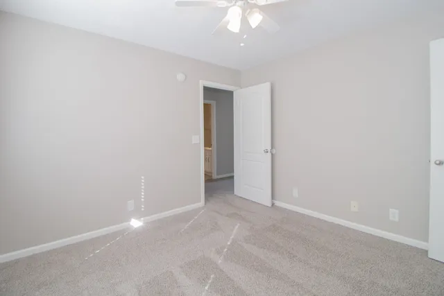 an empty room with a chandelier fan and windows