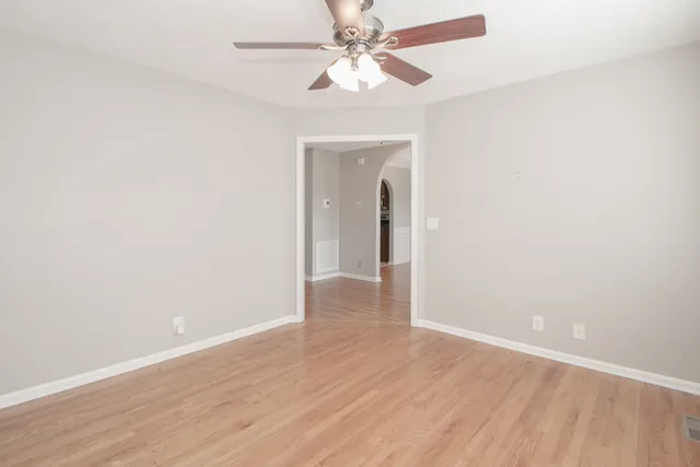 an empty room with wooden floor chandelier fan and closet area