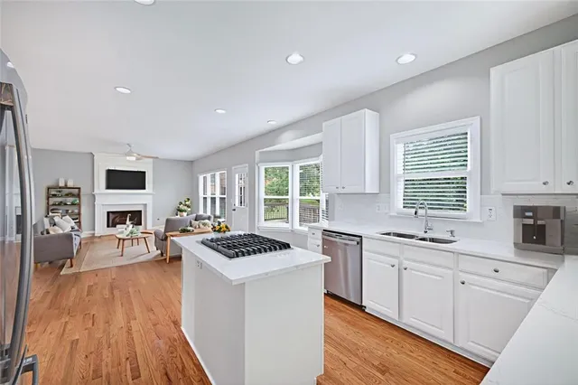 a kitchen with stainless steel appliances kitchen island hardwood floor sink stove and wooden cabinets
