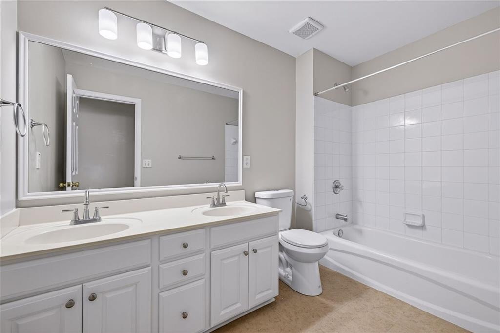 641 Olde Ivy Way Stone Mountain, GA 30087 - Photo 21 of 40 a spacious bathroom with a double vanity sink toilet mirror and bathtub
