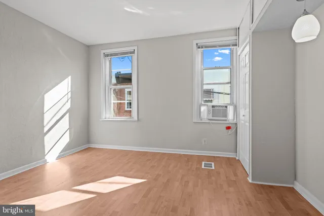 an empty room with wooden floor and windows
