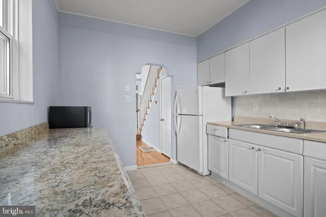 a kitchen with white cabinets and refrigerator