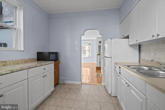 a kitchen with white cabinets and refrigerator