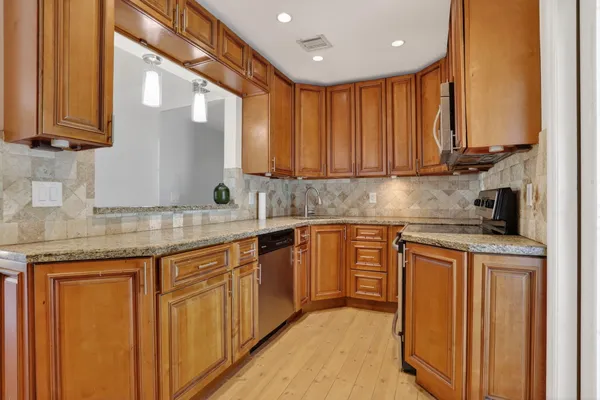 a kitchen with stainless steel appliances granite countertop a stove a sink and a microwave