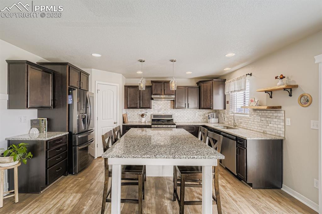 11329 Avena Road Peyton, CO 80831 - Photo 5 of 42 a kitchen with granite countertop kitchen island wooden cabinets and stainless steel appliances