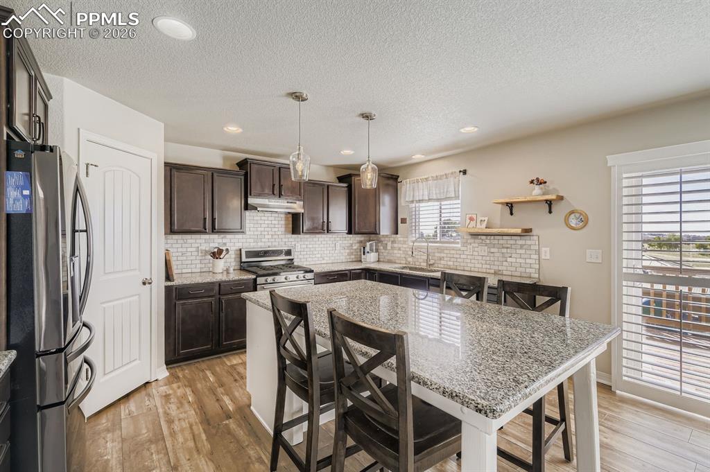 11329 Avena Road Peyton, CO 80831 - Photo 8 of 42 a kitchen with stainless steel appliances granite countertop a kitchen island hardwood floor and a sink
