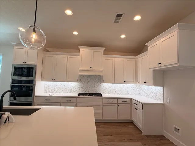 a kitchen with kitchen island granite countertop stainless steel appliances a stove oven and a white cabinets