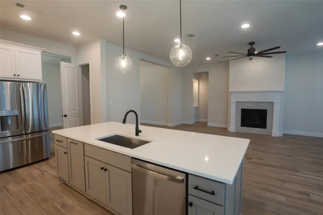 a kitchen with kitchen island a sink stainless steel appliances and wooden floor