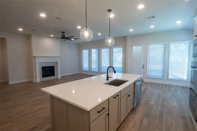 a kitchen with a stove center island a wooden floor and a fireplace