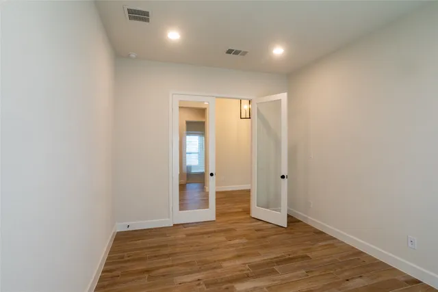 an empty room with wooden floor and windows
