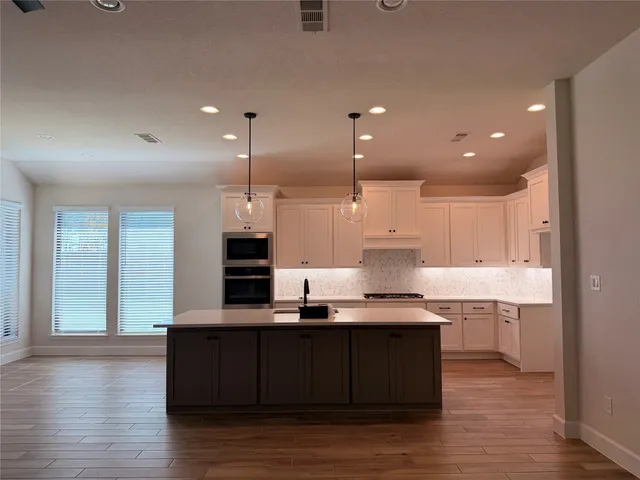 a kitchen with kitchen island granite countertop a sink cabinets and wooden floor