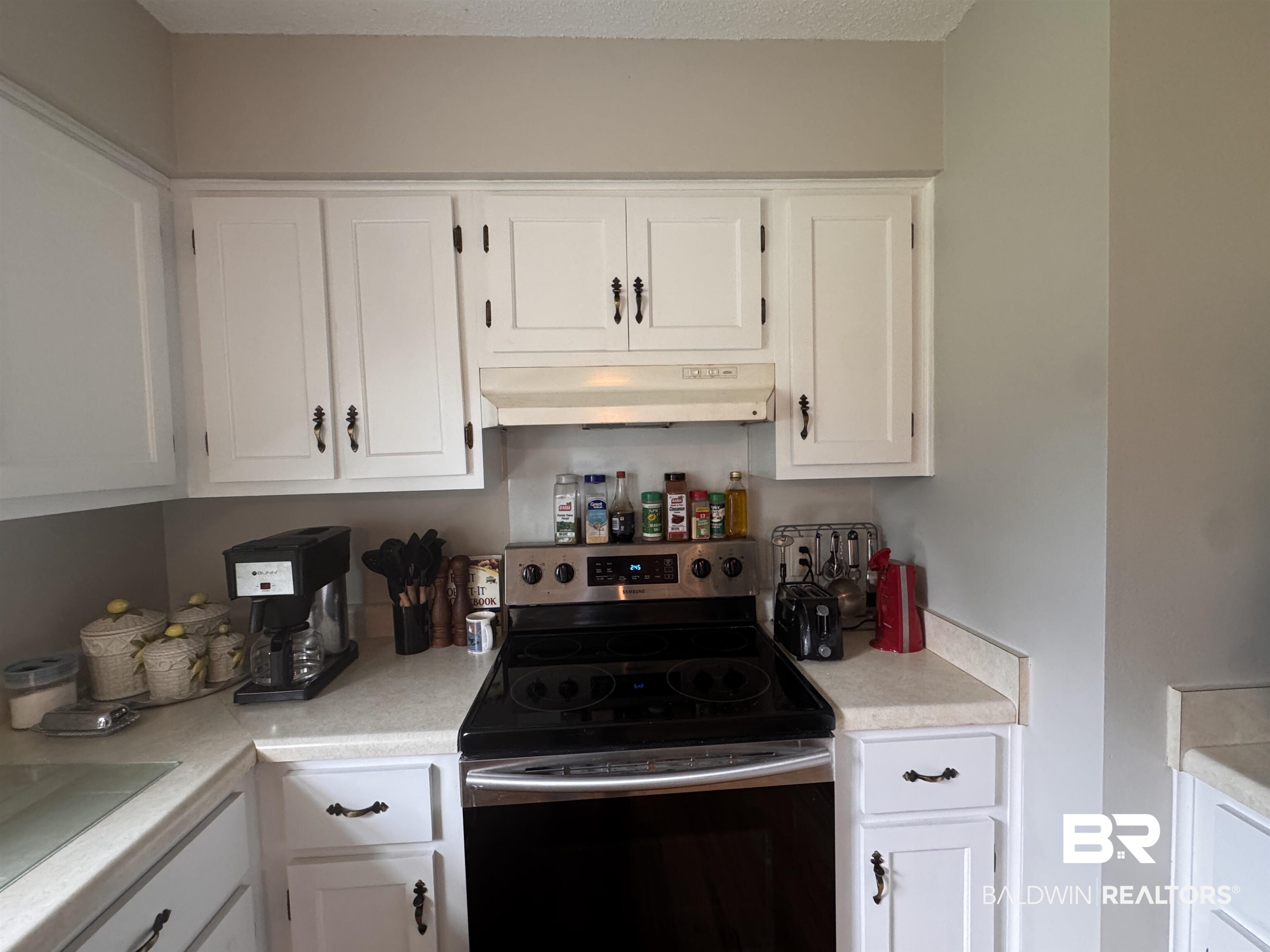 15148 Highland Circle Foley, AL 36535 - Photo 16 of 47 Kitchen featuring stainless steel electric range oven, under cabinet range hood, white cabinets, light countertops, and a sink