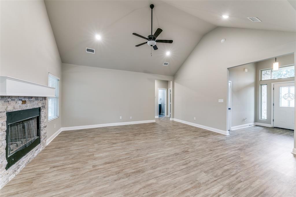 2844 Rodeo Drive Quinlan, TX 75474 - Photo 3 of 25 an empty room with wooden floor fireplace and windows