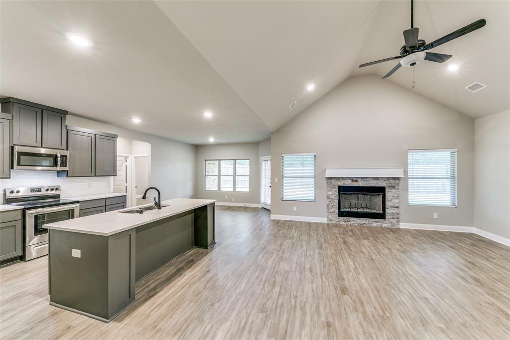 2844 Rodeo Drive Quinlan, TX 75474 - Photo 5 of 25 a large kitchen with stainless steel appliances granite countertop a stove top oven a sink dishwasher a dining table and chairs with wooden floor