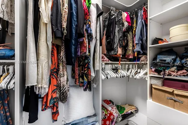a view of walk in closet with clothes and shoes