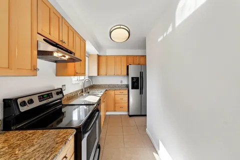 a kitchen with stainless steel appliances granite countertop a sink a stove and a refrigerator