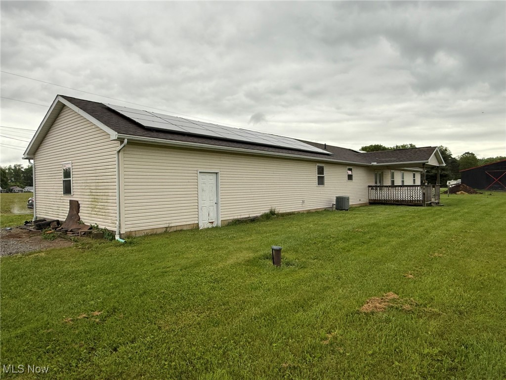 6920 Riverside Road Southeast Gnadenhutten, OH 44629 - Photo 35 of 41 Rear view of house featuring roof mounted solar panels, a lawn, and a wooden deck
