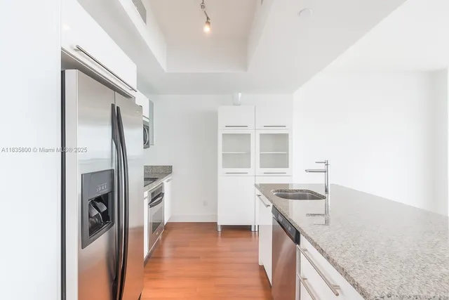 a kitchen with granite countertop a refrigerator and a sink