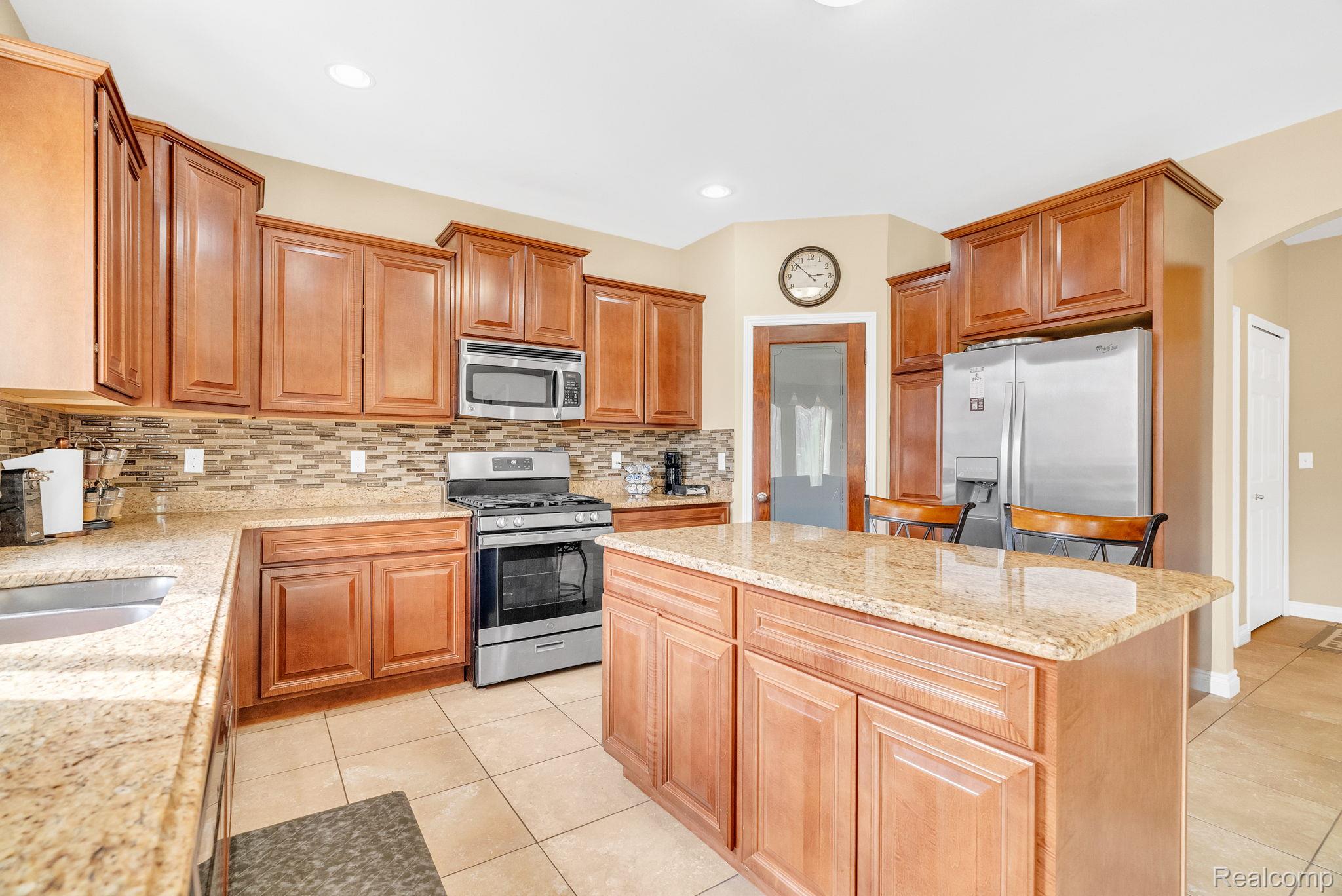 4122 Hawks Nest Road Utica, MI 48317 - Photo 28 of 74 Kitchen featuring stainless steel appliances, arched walkways, light stone countertops, a kitchen island, and light tile patterned flooring