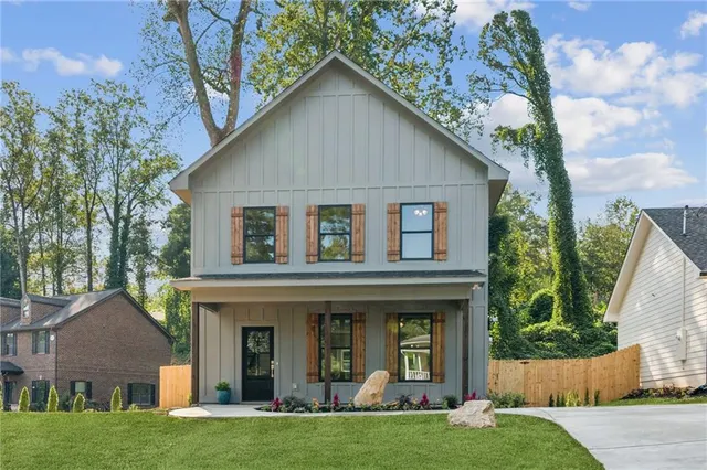 a view of a white house with a small yard and large trees