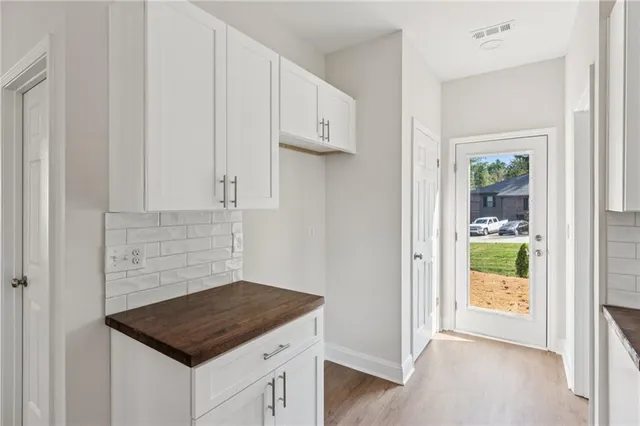 an empty room with wooden floor chandelier fan and windows