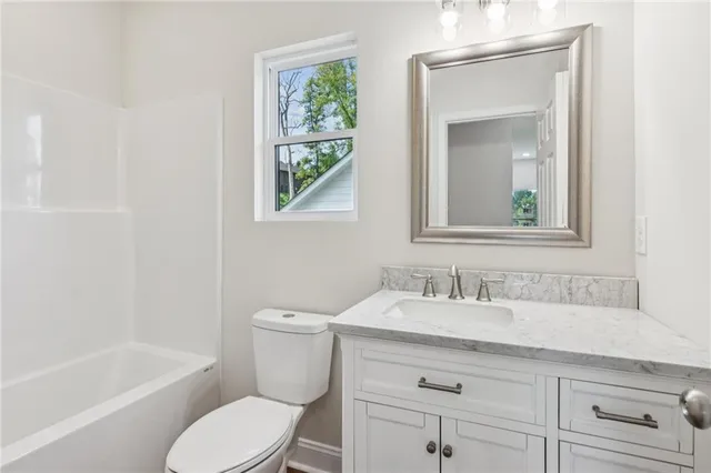 a bathroom with a granite countertop toilet a sink a mirror and a window