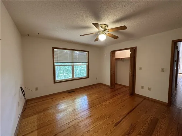 a view of empty room with wooden floor and fan
