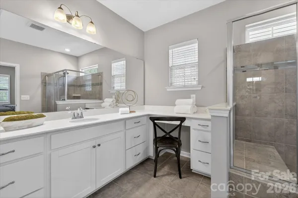 a bathroom with a sink double vanity granite tub shower and a mirror