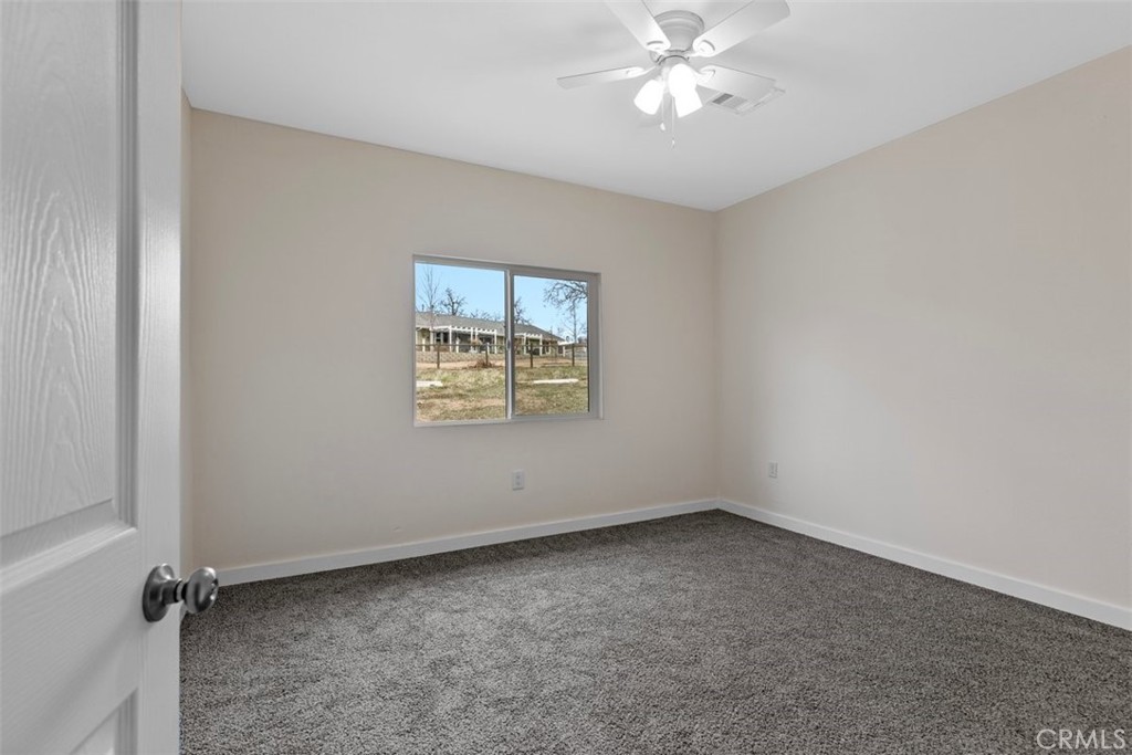 28551 Delaware Drive Tehachapi, CA 93561 - Photo 15 of 34 an empty room with a chandelier fan and windows