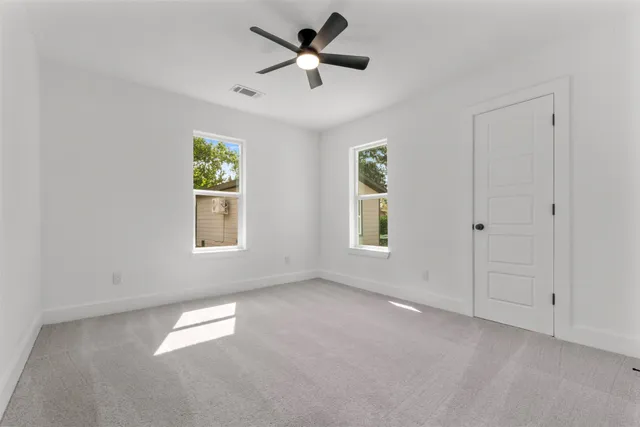 an empty room with windows and a ceiling fan